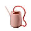 Pink indoor watering can with red scalloped handle and spout on a white background